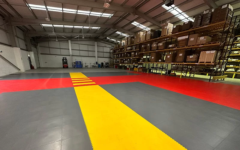A warehouse using ecotile flooring grey, yellow and red to create walkways